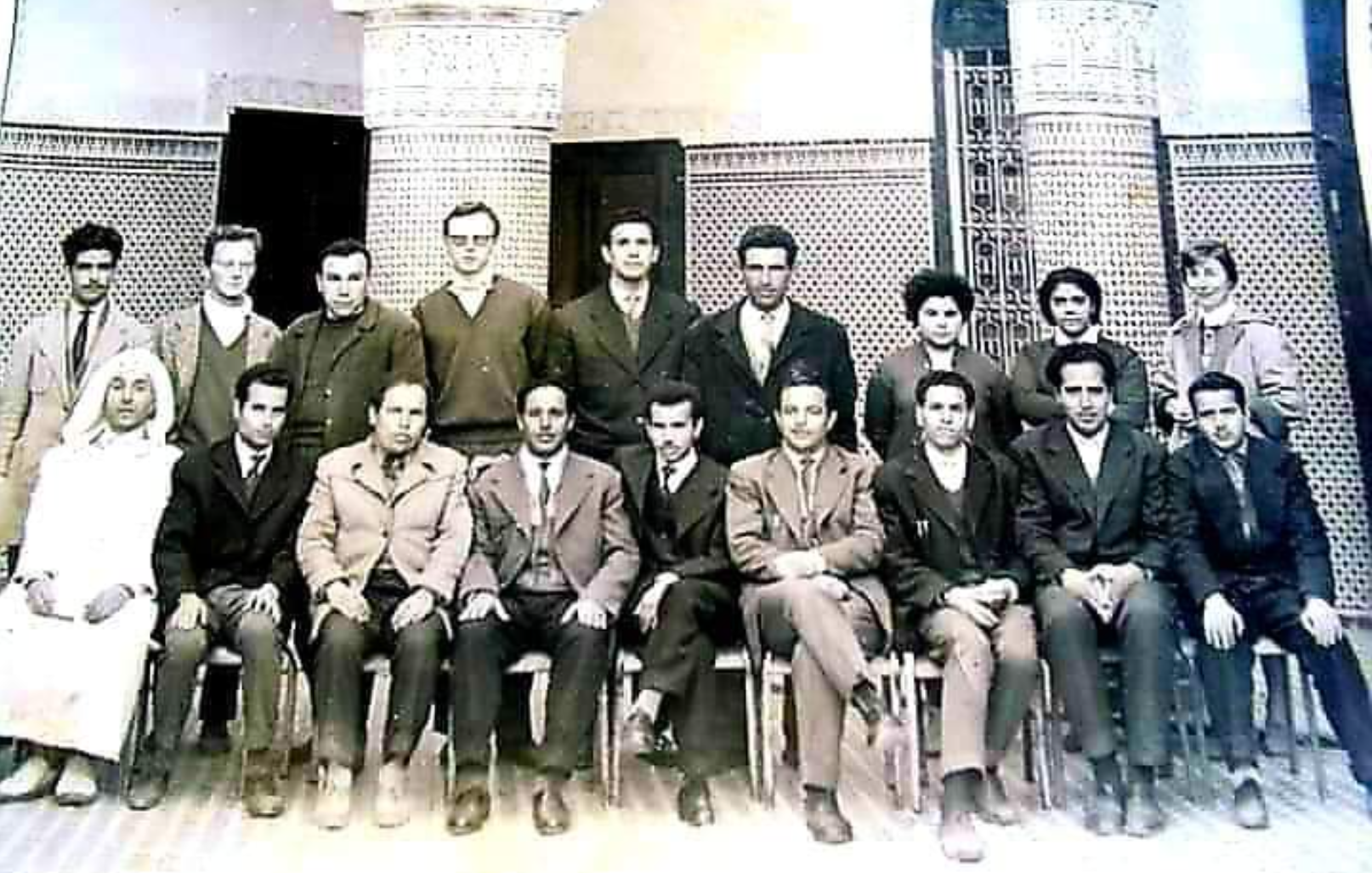 People in professional dress pose facing the camera with one row seated and another standing behind them. The photograph is in black and white.