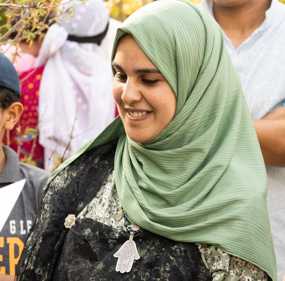 A young hijabi woman wears a silver necklace that resembles an upside-down hand